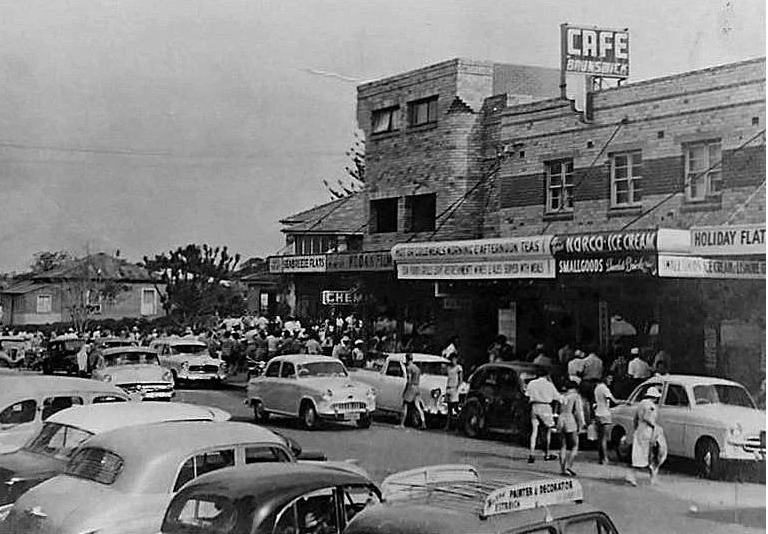 Vintage black and white photo of a shopping center with people and cars in Brunswick Heads, NSW.